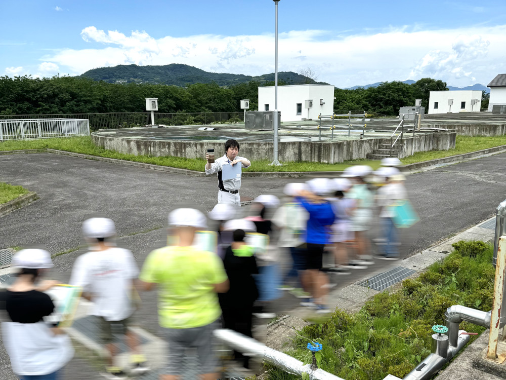 従業員が小学生へ排水施設の説明をしている写真