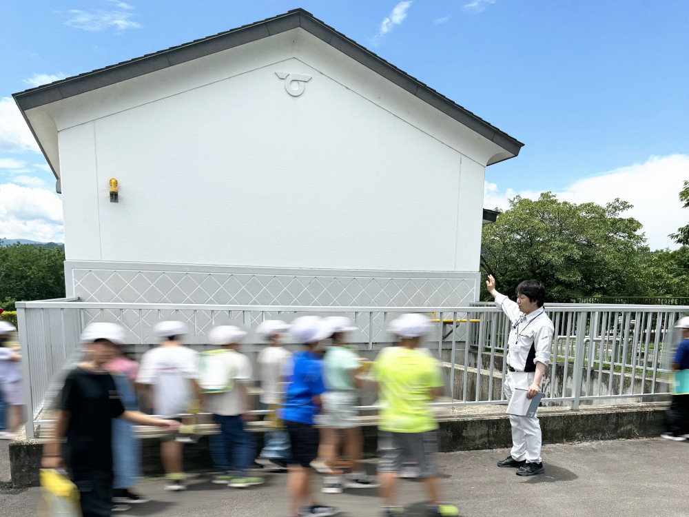 従業員が小学生へ排水施設の説明をしている写真